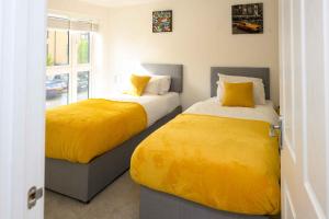two beds with yellow sheets in a room at Luxury 5 Bedroom House in Chatham