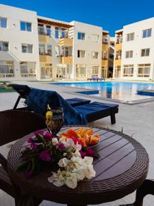 a table with a bowl of fruit and flowers on it next to a pool at Port Ghalib Apartments in Port Ghalib