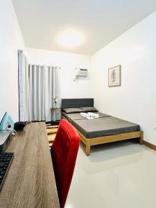 1 dormitorio con cama, escritorio y silla roja en Feel at Home Gensan Wi-fi Netflix Carport Hot Shower BBQ Grill, en General Santos