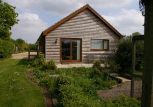 a small house with a garden in front of it at Oak Tree Cottage in Old Buckenham