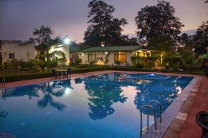 a swimming pool in front of a house at night at De Floresta Resort in Rāmnagar