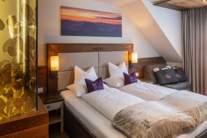 a bedroom with a large white bed with purple pillows at Wander- und Wellnesshotel Kanzler in Bad Mitterndorf