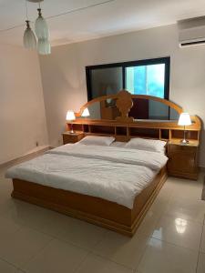 Schlafzimmer mit einem großen Bett mit einem Kopfteil aus Holz in der Unterkunft فيلاً بالقرب من البحر in Al Fanātīr