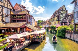 un gruppo di persone che cavalcano barche lungo un fiume con edifici di Appartement L'Authentique de la Petite Venise a Colmar