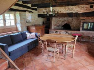 ein Wohnzimmer mit einem Tisch und einem blauen Sofa in der Unterkunft Gîte Fournil in Varaire