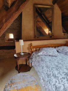 ein Schlafzimmer mit einem Bett und einem Tisch mit einer Lampe in der Unterkunft Gîte Fournil in Varaire