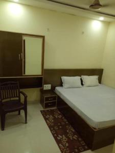 a bedroom with a bed and a chair and a mirror at Swastik Guest House Inn Varanasi in Varanasi