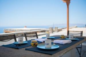 una mesa con platos y tazas de café en la playa en blue paradise villa, en Sifnos