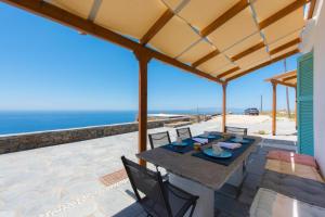 un patio con mesa, sillas y el océano en blue paradise villa, en Sifnos