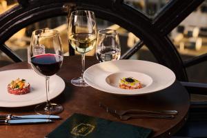 a table with two plates of food and wine glasses at Hotel Gotham in Manchester