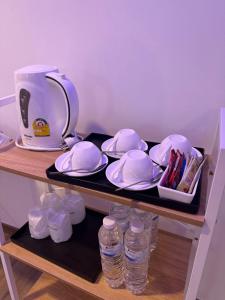 uma chaleira, pratos e garrafas de água numa prateleira em Neo Hatyai Hotel em Hat Yai