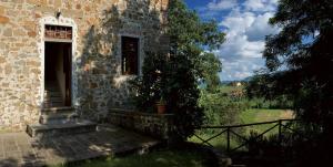 un edificio con una puerta y un árbol al lado en Palagina la cascina, en Figline Valdarno