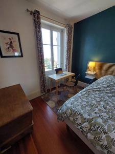 a bedroom with a bed and a desk with a laptop at Le Mirabeau Vue Lac in Évian-les-Bains