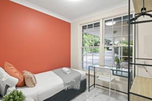 1 dormitorio con paredes de color naranja, 1 cama y ventana en Single Room in Pymble Sleeps 1, en Pymble