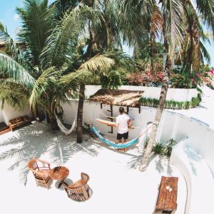 a man standing in a hammock next to a resort pool at TWIN PALMS 'Surfhouse' in Thulusdhoo +41 photos
