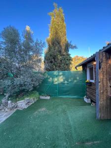 einen Hinterhof mit einem Zaun und einem grünen Garten in der Unterkunft Cabaña del olivo in Paredes de Buitrago