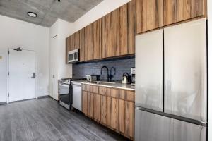 eine Küche mit Holzschränken und einem Kühlschrank aus Edelstahl in der Unterkunft Blueground West Loop gym roof nr Union Park CHI-1058 in Chicago