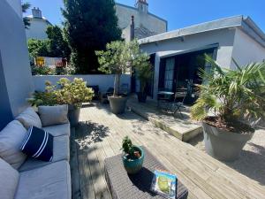 eine Terrasse mit Topfpflanzen und eine Couch auf einer Terrasse in der Unterkunft Donvillaise 15 pers : jacuzzi, 8 min à pied plage in Donville-les-Bains