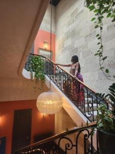 una mujer caminando por una escalera con una lámpara de araña en La Maison Mulatô, demeure privée d'hôtes, piscine & spa Libourne, Saint-Emilion en Libourne