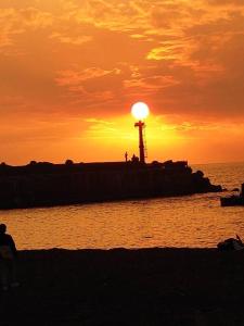 a sunset over the water with a lighthouse on a pier at 愛琴海岸精品民宿 in Fangliao