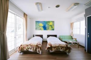 Zimmer mit 2 Betten, einem Sofa und Fenstern in der Unterkunft Hotel Kailani in Oshima