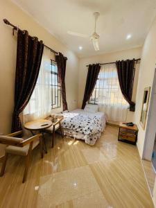 een slaapkamer met een bed en een tafel en ramen bij Shooting star Lodge in Dodoma