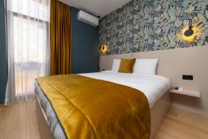 sypialnia z dużym łóżkiem z żółtym kocem w obiekcie Hotel Ma Belle w Prisztinie