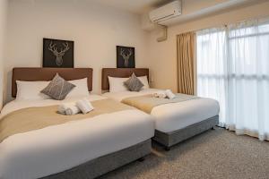 duas camas num quarto de hotel com uma janela em b&通天閣店 em Osaka