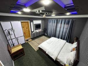 a bedroom with a white bed and a television at Signature Skardu Hotel in Skardu