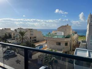 einen Balkon mit Blick auf Gebäude und das Meer in der Unterkunft נוף נתניה in Netanya