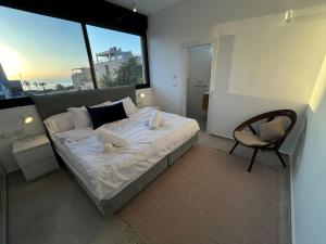 ein Schlafzimmer mit einem Bett, einem Stuhl und einem Fenster in der Unterkunft נוף נתניה in Netanya