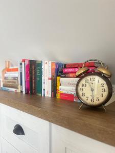 a clock sitting on a shelf with books at Cudne Manowce ogrodzony domek na wyłączność wśród ciszy i natury u stóp Gór Izerskich in Giebułtów