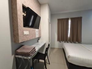a room with a bed and a desk with a television at Mozu Hotel Sri Hartamas in Kuala Lumpur