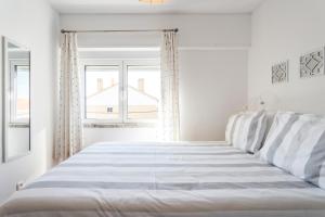 a white bedroom with a bed and two windows at Beach House Cascais in Estoril