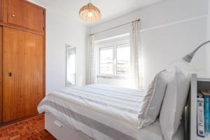a white bedroom with a bed and a window at Beach House Cascais in Estoril