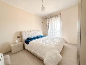 une chambre blanche avec un lit blanc et une fenêtre dans l'établissement Tirana Family Suite, à Kashari