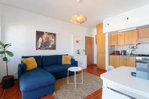 a living room with a blue couch and a kitchen at Beach House Cascais in Estoril