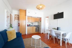 a living room with a blue couch and a kitchen at Beach House Cascais in Estoril