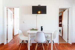 a dining room with a white table and white chairs at Beach House Cascais in Estoril