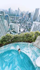 a person swimming in a swimming pool on top of a city at The Serene Escape Rockwell Makati City View 1BR in Manila