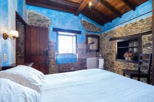 1 dormitorio con cama y pared de piedra en La Casona Del Cura III, en Pravia