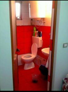 a red bathroom with a toilet and a sink at Hotel Rozafa Velipoje in Baks-Rrjoll