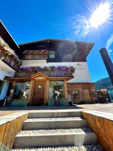 a building with stairs in front of it with the sun in the sky at Hotel Riva Sport & Wellness in Vione