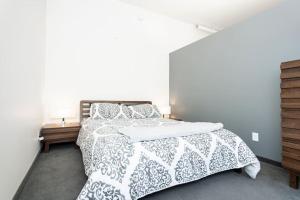 una camera da letto con un letto con un piumone e cuscini bianchi di Premium 2BD Loft DT Heated Parking Rooftop Patio BBQ Gym Coffee a Winnipeg