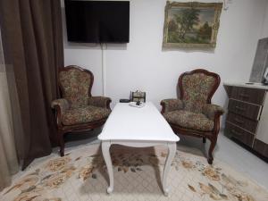 salon z 2 krzesłami i białym stołem w obiekcie IN Apartments AirPort w mieście Podgorica