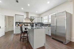 a kitchen with white cabinets and a stainless steel refrigerator at Modern Escape in Historic District in Mobile