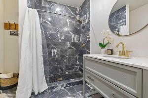 een badkamer met een douche, een wastafel en een spiegel bij Modern Escape in Historic District in Mobile