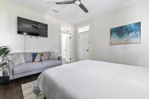 ein weißes Schlafzimmer mit einem Bett und einem Sofa in der Unterkunft Modern Escape in Historic District in Mobile