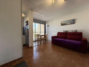 een woonkamer met een paarse bank en een keuken bij Appartement Gruissan, 1 pièce, 3 personnes - FR-1-229-882 in Gruissan