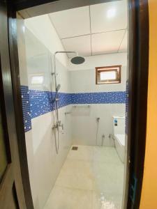ein Bad mit blau gefliesten Wänden und einer Dusche in der Unterkunft Thirasara Family Garden in Medawachchiya